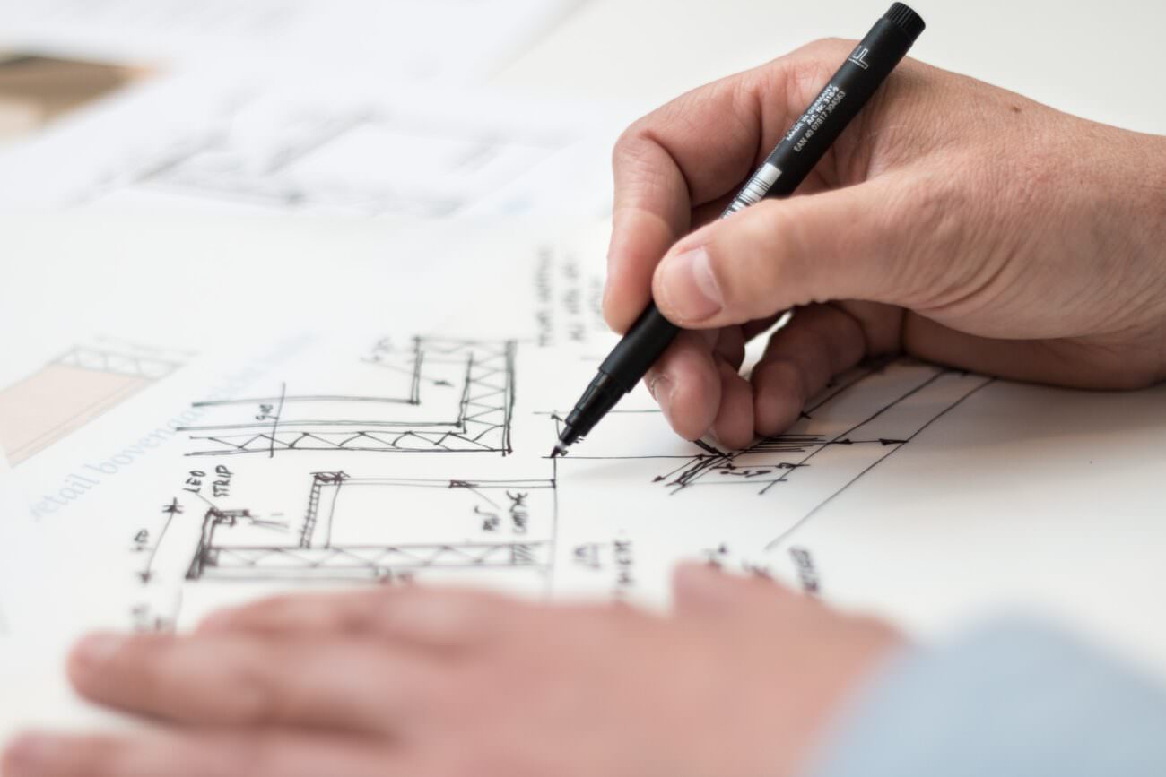 A businessperson is drawing a technical architectural sketch with a black pen