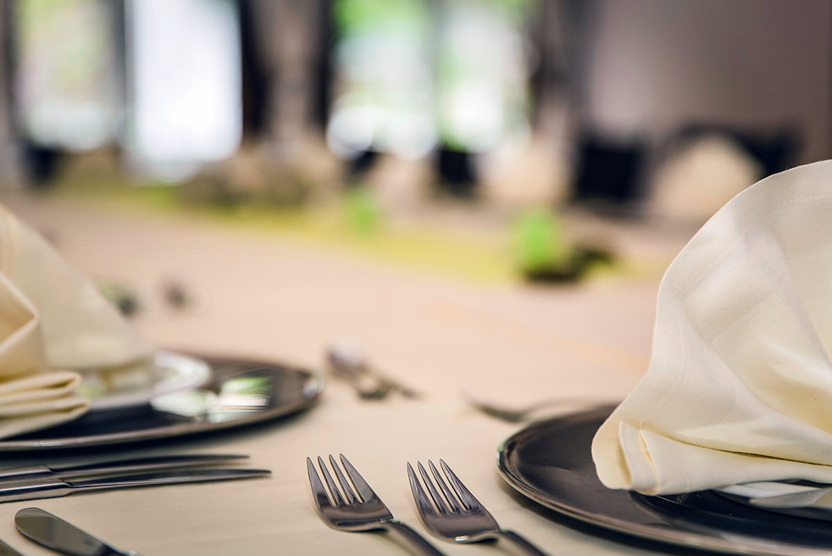 Plates, napkins, and cutlery are arranged on a table, ready for dinner